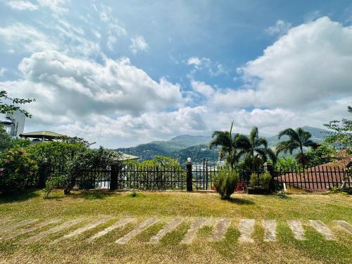 a fence with palm trees and a mountain in the background at The Views Kandy - 360 Mountain View in Kandy