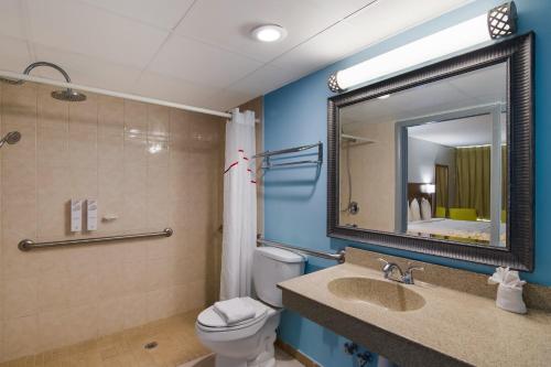 a bathroom with a toilet and a sink and a mirror at HomeTowne Studios by Red Roof Vero Beach - I-95 in Vero Beach