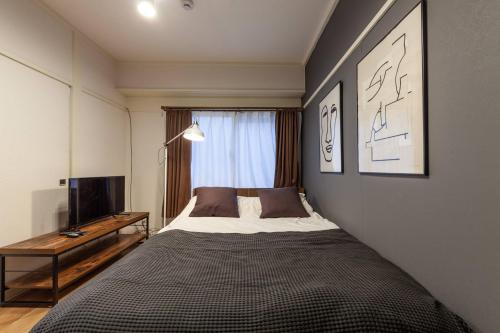a bedroom with a large bed and a television at Tsukimura Building in Tokyo