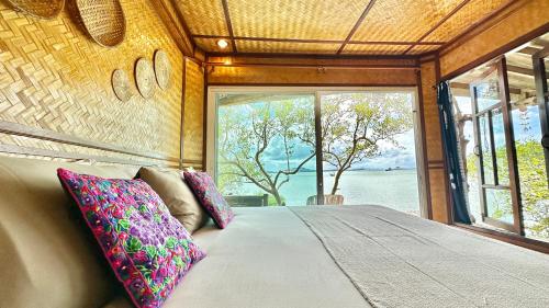 a bed in a room with a large window at Deep House Sea View in Ko Lanta