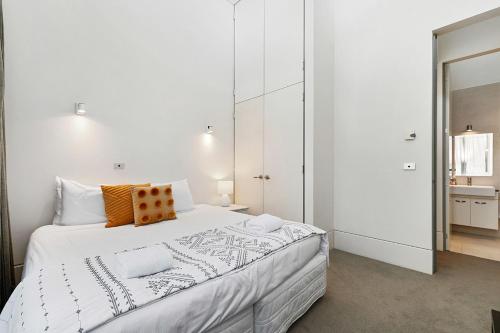 a white bedroom with a large bed with an orange pillow at Taupo Penthouse in Taupo
