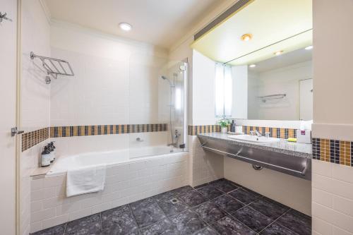 a bathroom with a tub and a sink and a mirror at Charming Studio Apartment in Auckland Central in Auckland