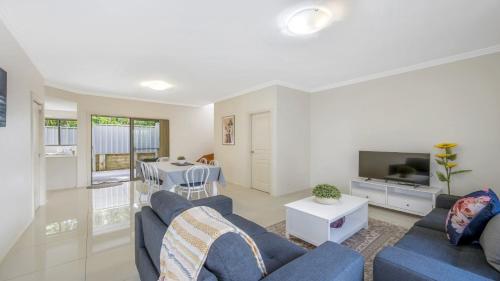 a living room with a blue couch and a tv at Anne Street Monte - Vista in Port Macquarie