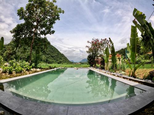 a swimming pool in a garden with mountains in the background at Thavill Retreat HaGiang in Ha Giang