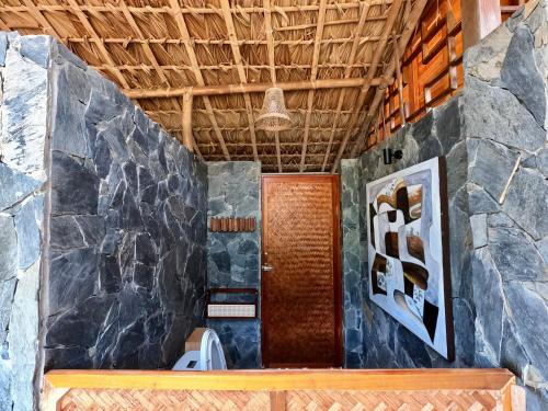 a bathroom with a toilet and a stone wall at Thavill Retreat HaGiang in Ha Giang