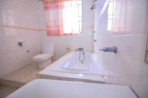 ein Badezimmer mit einer Badewanne, einem WC und einem Waschbecken in der Unterkunft Kiverly Guest House in Atasomanso