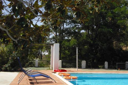 a swimming pool with two blue chairs and a swimming at Casas Cueva y Cortijo La Tala en Guadix in Guadix