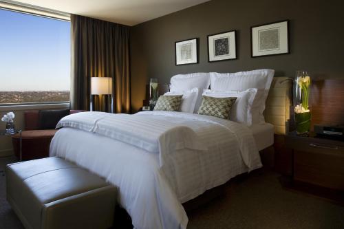a bedroom with a large white bed with a window at Pullman Sydney Olympic Park in Sydney
