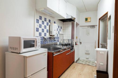 a small kitchen with a sink and a microwave at 新宿から快速15分の三鷹駅徒歩3分 最大5名 ゆったり和室【MITAKA NAGOMI ROOM】　 in Musashino