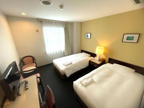 a hotel room with two beds and a desk at Smile Hotel Yonago in Yonago