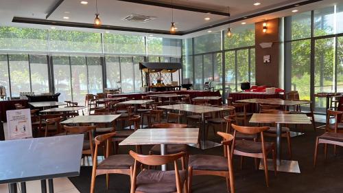 un restaurante con mesas, sillas y ventanas en D'Wharf Hotel & Serviced Residence en Port Dickson