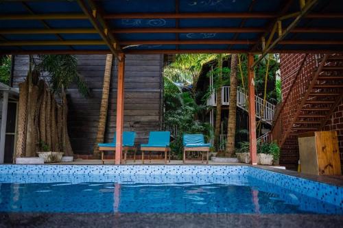 a swimming pool with blue chairs next to a house at KAYANIV Ayurveda & Wellness Resort in Mandrem