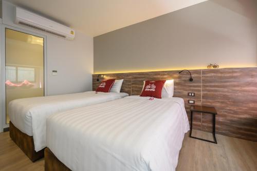 two beds in a hotel room with white and red pillows at Tour De Phuket Hotel - SHA Plus in Thalang