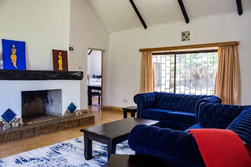 a living room with blue couches and a fireplace at Maanzoni - Ndoto House ,Athi River by Nest & Nomad in Machakos