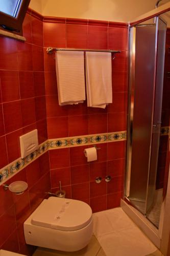 a red tiled bathroom with a toilet and a shower at Villa Cristina in Giardini Naxos