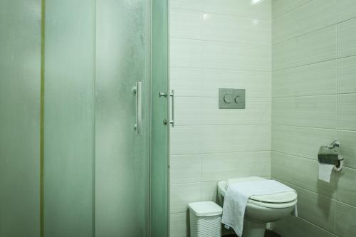a white bathroom with a toilet and a shower at The Printhouse - Downtown Boutique Apartments by Sea N' Rent in Haifa