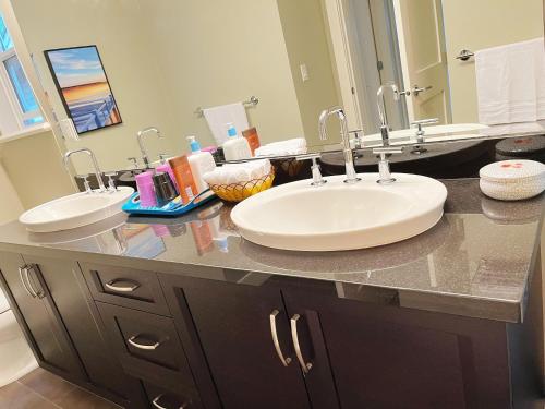 a bathroom with two sinks and a large mirror at Derbyshire House in Coquitlam