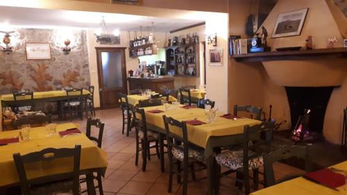 a restaurant with yellow tables and chairs and a fireplace at Agriturismo Fonte Magria in Abbadia San Salvatore