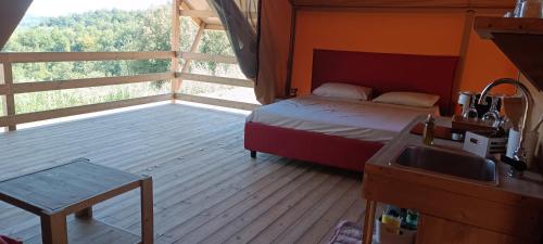 a bedroom with a bed and a balcony with a sink at Glamping Podere Poggiagrilli in San Gervasio
