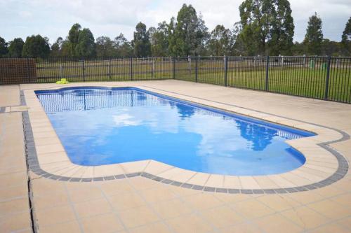 a swimming pool with blue water in a yard at Excellent campsite Hunter Valley in Pokolbin