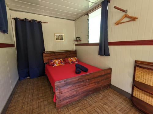 een slaapkamer met een rood bed in een kamer bij Noho Mai in Nuku Hiva