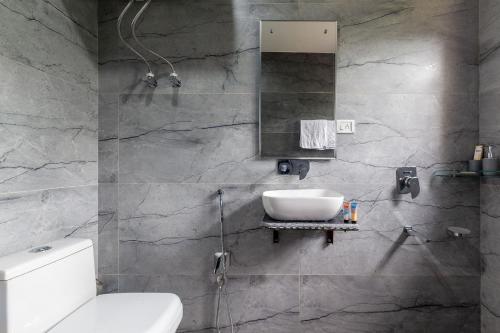 La salle de bains est pourvue d'un lavabo, de toilettes et d'un miroir. dans l'établissement StayVista at Buhayra Lakefront, à Srinagar