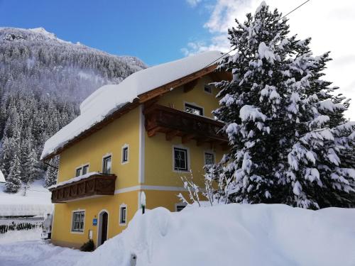 Haus Anika Ferienwohnung في مالنيتز: أمامه بيت أصفر مغطى بالثلج