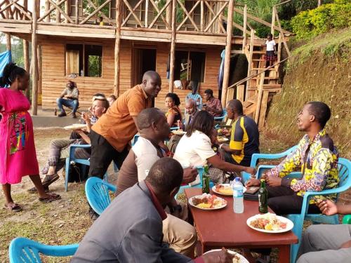 Un gruppo di persone seduti intorno a un tavolo che mangiano di Noah's Ark Campsite & Restaurant a Fort Portal
