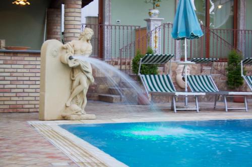 a statue next to a pool with a fountain at Villa Cristina in Giardini Naxos