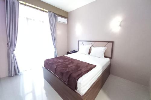 a bedroom with a bed and a large window at Hotel O Lavina Guesthouse in Dumai