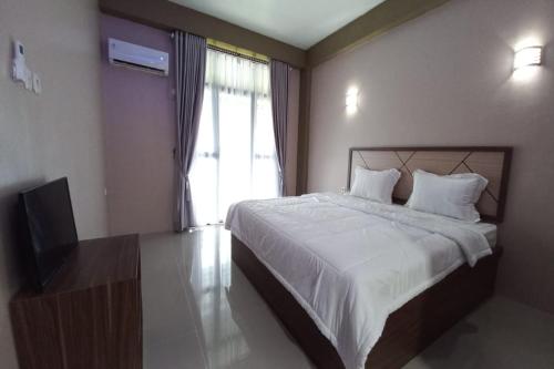 a bedroom with a large bed and a television at Hotel O Lavina Guesthouse in Dumai