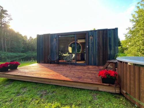 een tiny house met een terras in de tuin bij Reborn Cabins in Pabaži