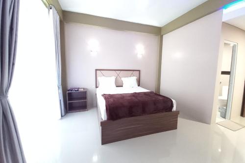 a bedroom with a bed and a large window at Hotel O Lavina Guesthouse in Dumai