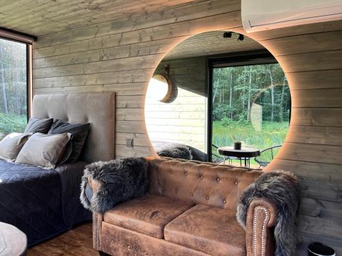 a living room with a brown couch and a window at Reborn Cabins in Pabaži