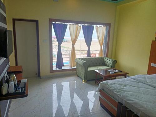 a bedroom with a bed and a couch and a window at ST Apple Beach Resort Mandarmani in Mandarmoni