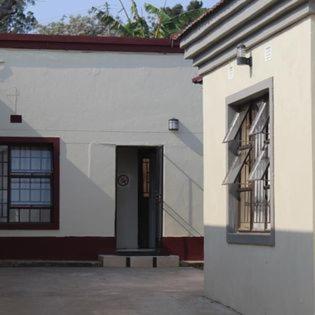 un edificio blanco con puerta y ventana en Ngwane Park Guest House en Manzini