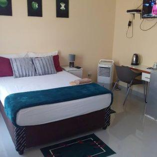 1 dormitorio con 1 cama, escritorio y en Ngwane Park Guest House en Manzini