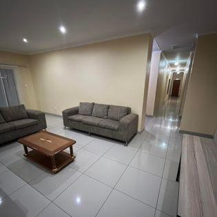Sala de estar con 2 sofás y mesa de centro en Ngwane Park Guest House, en Manzini