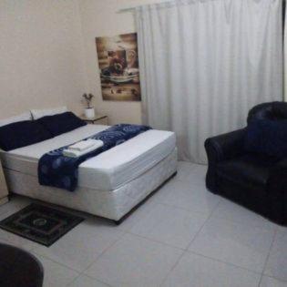1 dormitorio con 1 cama y 1 silla en Ngwane Park Guest House en Manzini