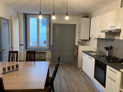 a kitchen with a wooden table and a large window at LA FINNOISE in Fains-les-Sources