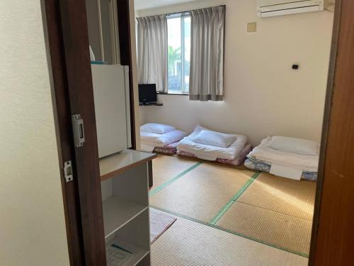 Zimmer mit 2 Betten in einem Zimmer mit einer Tür in der Unterkunft Southern Village Okinawa - Vacation STAY 09978v in Kishaba