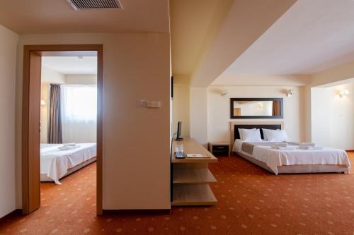 a hotel room with two beds and a mirror at Hotel Oxford Inns&Suites in Timişoara