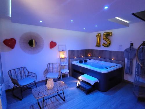 een grote kamer met een bad en 2 stoelen bij L'oxybulles et Spa in Friville-Escarbotin