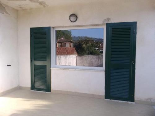 une fenêtre avec des portes vertes et une horloge sur un mur dans l'établissement Villetta a schiera con giardino e terrazza-S.Marco di C.te, à San Marco di Castellabate