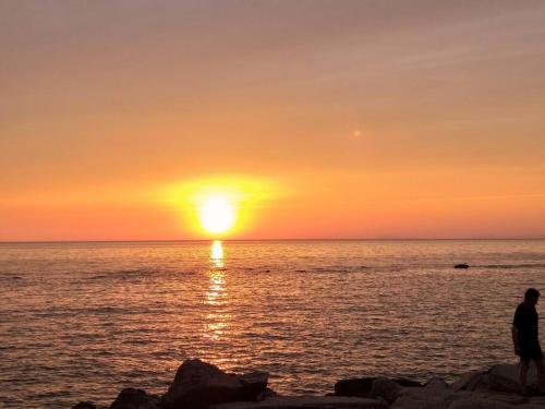 - une personne debout sur la plage pour observer le coucher du soleil dans l'établissement Villetta a schiera con giardino e terrazza-S.Marco di C.te, à San Marco di Castellabate