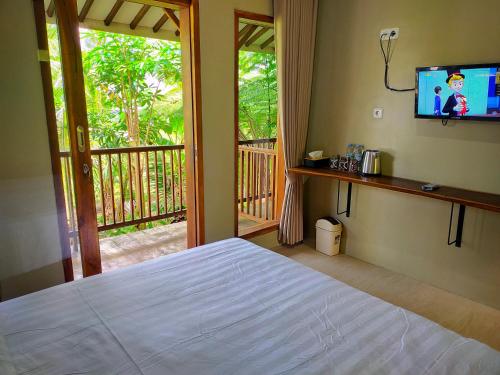 バニュワンギにあるAUREIRIN Guesthouseのベッドルーム(ベッド1台、テレビ、バルコニー付)