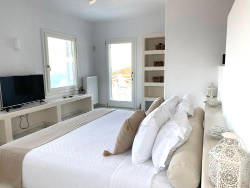 a white bedroom with a large bed with white pillows at Villa Artemis in Agios Georgios