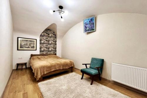 a bedroom with a bed and a green chair at Unique Apartment in the Center of Tbilisi in Tbilisi City