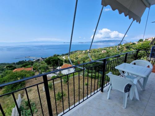 uma varanda com uma mesa e cadeiras e o oceano em Skopelos House Nikols em Loutraki