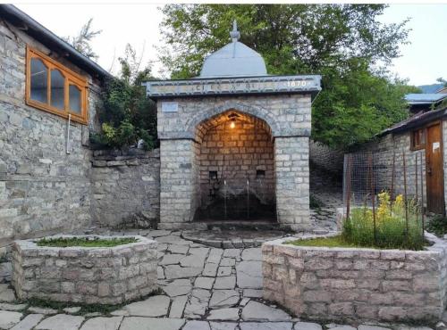 una chimenea de piedra en el patio trasero de una casa en Lahij - Ismayilov's Hotel, en Lahıc